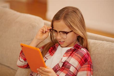 Cute Blonde Girl With A Device In Hands Sitting On The Sofa Stock Photo Image Of Longhaired