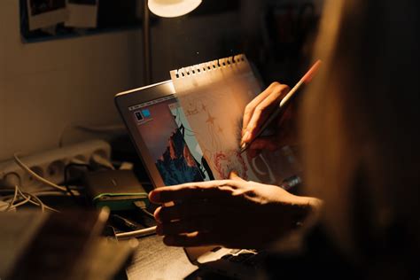 A Person Writing on White Paper over Laptop Screen · Free Stock Photo