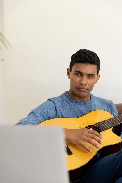 Premium Photo Biracial Man Sitting On Sofa Playing Guitar And Using