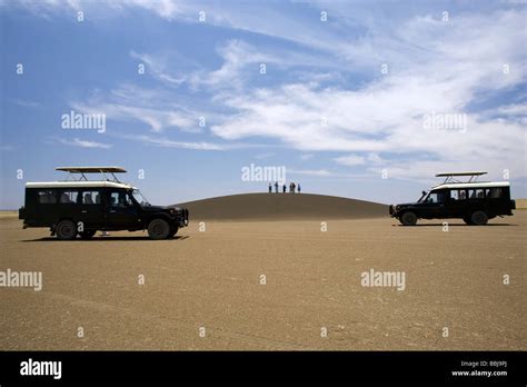 Safari Vehicles And Group Of People On Shifting Sands Dune Near