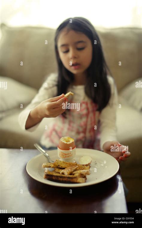 Fille mange un œuf avec du pain grillé pour le petit déjeuner des