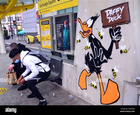 Men sit next to an image of Daffy Duck cartoon character, part of a ...