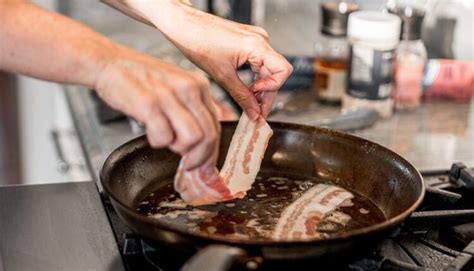 A Person Is Cooking Some Meat In A Frying Pan