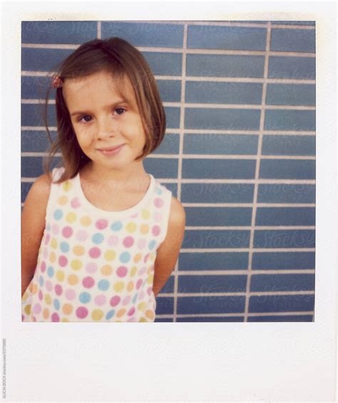 Vintage Polaroid Portrait Of A Cute Girl Standing Against A Blue Wall