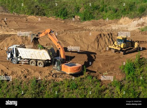 Excavator Loading Dumper Truck With Sand At Construction Site Stock