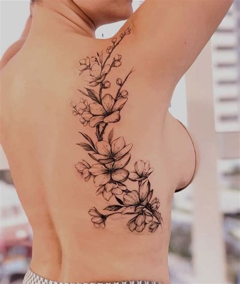 A Woman S Back Tattoo With Flowers On Her Left Shoulder And The Upper