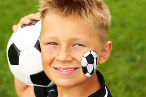 Muchacho Joven Con El Balón Pintado De La Cara Y De Fútbol Imagen de