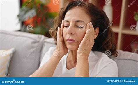 Middle Age Hispanic Woman Suffering For Headache Sitting On Sofa At