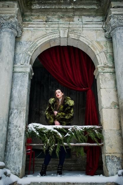 Premium Photo Brunette Girl In Green Fur Coat Against Old Arch With Columns And Red Curtains