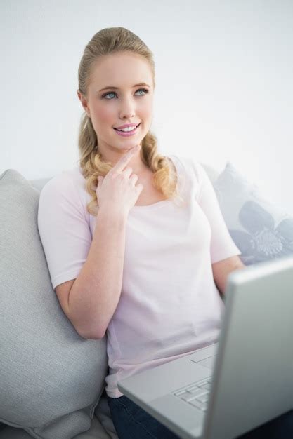 Premium Photo Casual Thoughtful Blonde Sitting On Couch Using Laptop