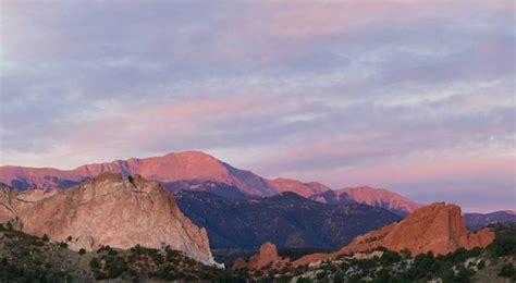 The Mountains Are Covered In Pink And Purple Clouds As The Sun Is