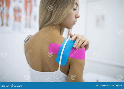 Kinesiology Taping Treatment With Blue And Pink Tape On Female Patient