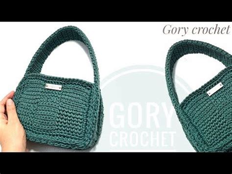 A Hand Holding A Green Crochet Purse With The Handles Open And It S Inside