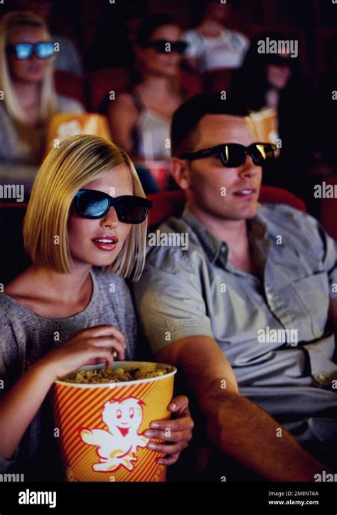 Enthrall Your Senses A Couple Sitting And Eating Popcorn While