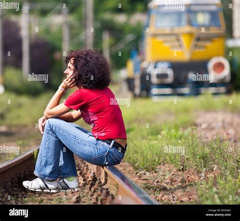 Joven pelirroja mujer sentada sobre las vías del tren en un ferrocarril