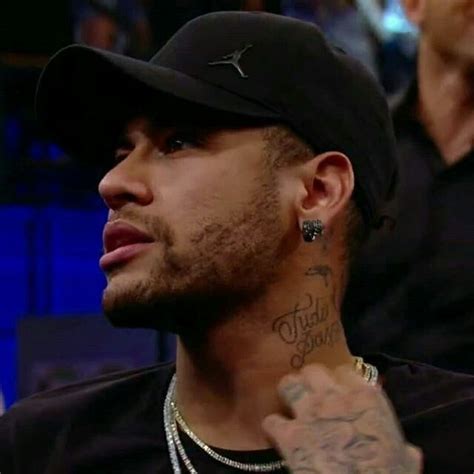 A Close Up Of A Person Wearing A Baseball Cap And Tattoos On His Arm