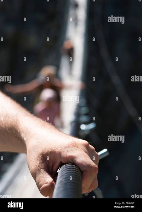 Man Holding Onto Railing On Rope Bridge Stock Photo Alamy