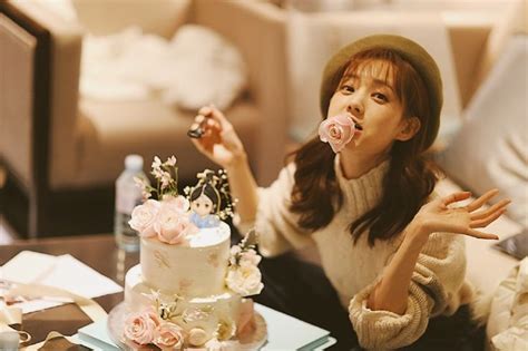 A Woman Blowing Out Pink Roses On Top Of A White Cake Sitting On A Table