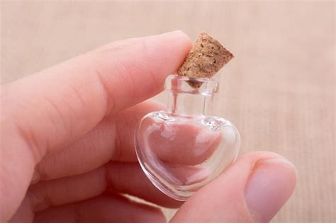 Premium Photo Heart Shaped Glass Bottle In Hand