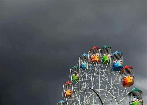 A Ferris Wheel With Many Colorful Windows On It S Side Under A Cloudy Sky