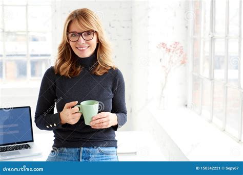 Beautiful Businesswoman Standing In The Office While Drinking Her