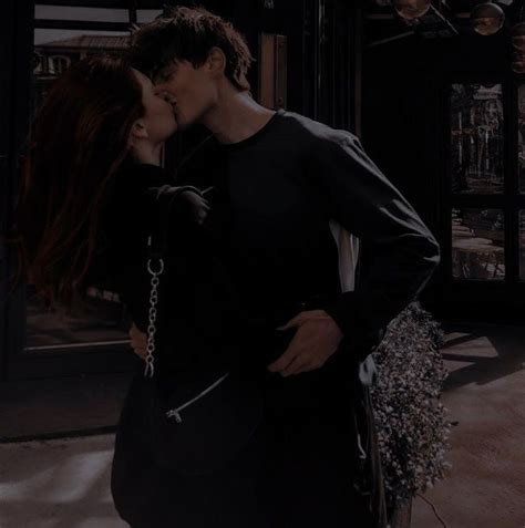 A Man And Woman Are Kissing In Front Of A Store Window With Their Hands