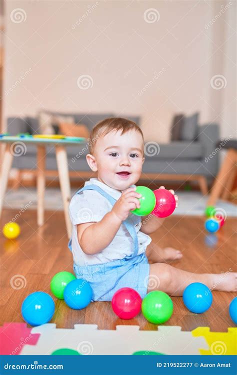 Beautiful Toddler Sitting On The Floor Playing With Small Colorful