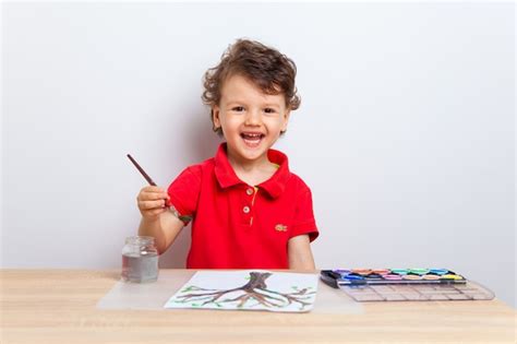 Premium Photo Cute Boy Drawing A Tree With Paints On A Paper Sheet