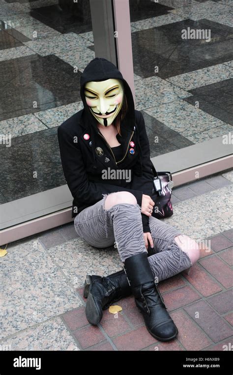 A female activist wearing a Guy Fawkes mask and a hoodie at a protest ...