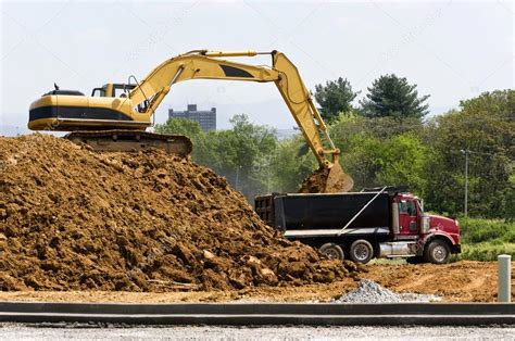 Excavator Loading Dump Truck At Construction Site Stock Photo By