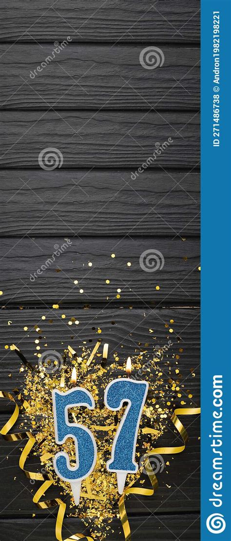 Number 57 Blue Celebration Candle And Gold Confetti On Dark Wooden