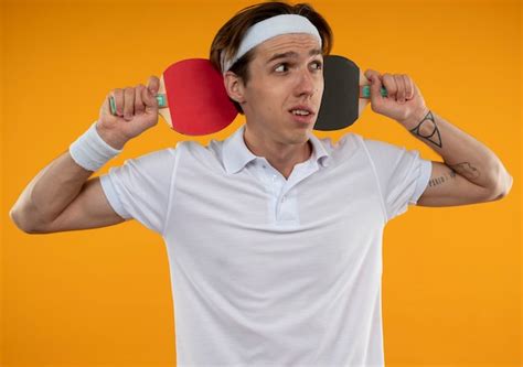 Free Photo Confused Young Sporty Guy Looking At Side Wearing Headband