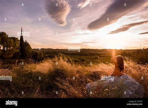 Girl sitting on rock looks over valley at sunset clouds in sky Stock Photo - Alamy