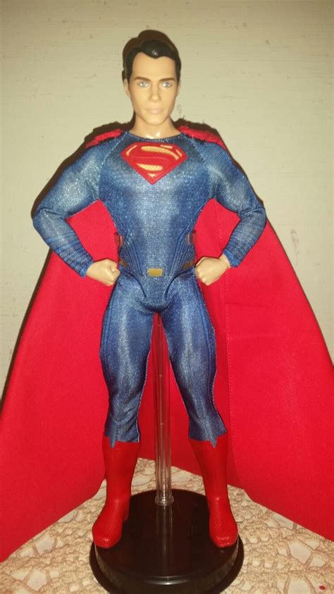 A Superman Action Figure Standing On Top Of A Table