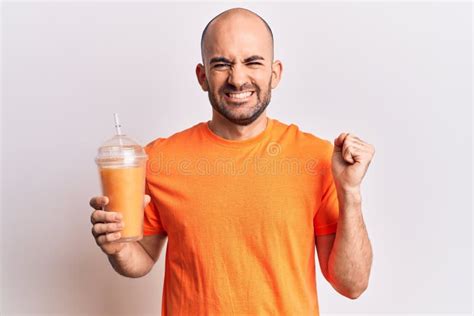 Young Handsome Bald Man Drinking Glass Of Healthy Orange Juice