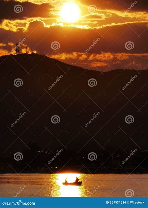 Vertical Shot Of A Bright Orange Sunset Sky Over A Lake With A