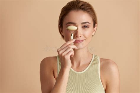 Face Massage Smiling Woman Using Jade Facial Roller For Skin Care