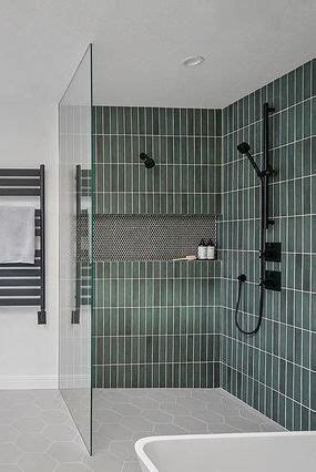 A Bathroom With Green Tiled Walls And Flooring Along With A White Bathtub