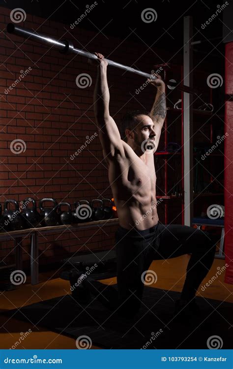 Homem Muscular Novo Uma Barra Do Barbell No Gym Foto De Stock