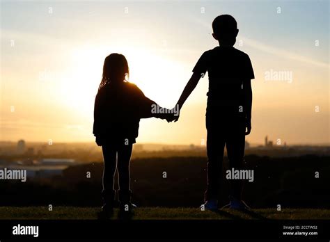 Silhouette of 2 young siblings watching the sun setting over Leeds ...