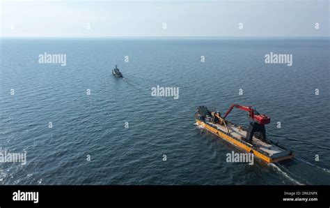 Tug Boat Travelling Across Open Ocean Pulling A Yellow Barge Loaded