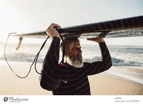 Caucasian Senior Man With Beard Carrying Surfboard On His Head A