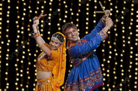 Portrait Of Happy Indian Couple In Traditional Wear Performing Dandiya