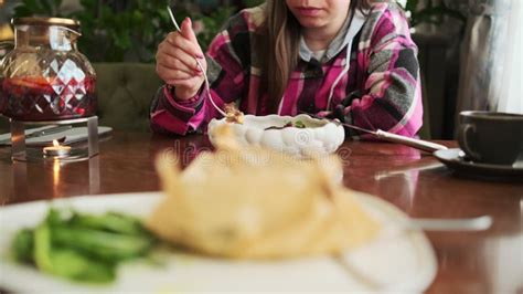 Female Sitting At Table With Plate Of Food A Woman Is Sitting At A