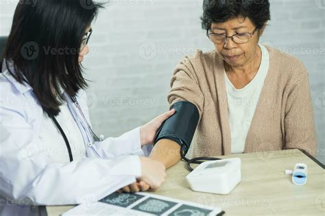 Woman doctor measuring blood pressure for elderly female patient on the