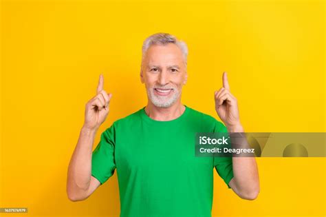 Photo Of Funny Positive Guy Dressed Green Tshirt Pointing Two Fingers Up Empty Space Isolated