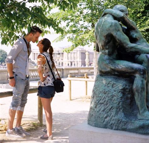 A Man And Woman Standing Next To A Statue