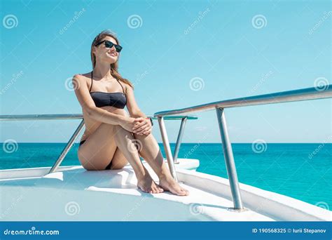 Portrait Of Hot Attractive Woman Sitting On Bow Of Yacht In Bikini