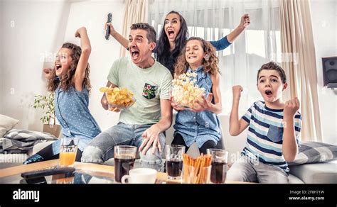 Family watching sports match on tv at home, cheering and shouting goal ...