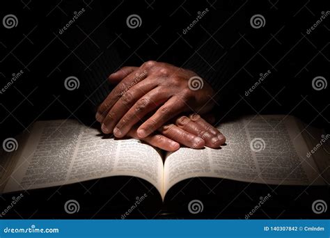 African American Man Praying With Hands On Top Of The Bible Stock Photo